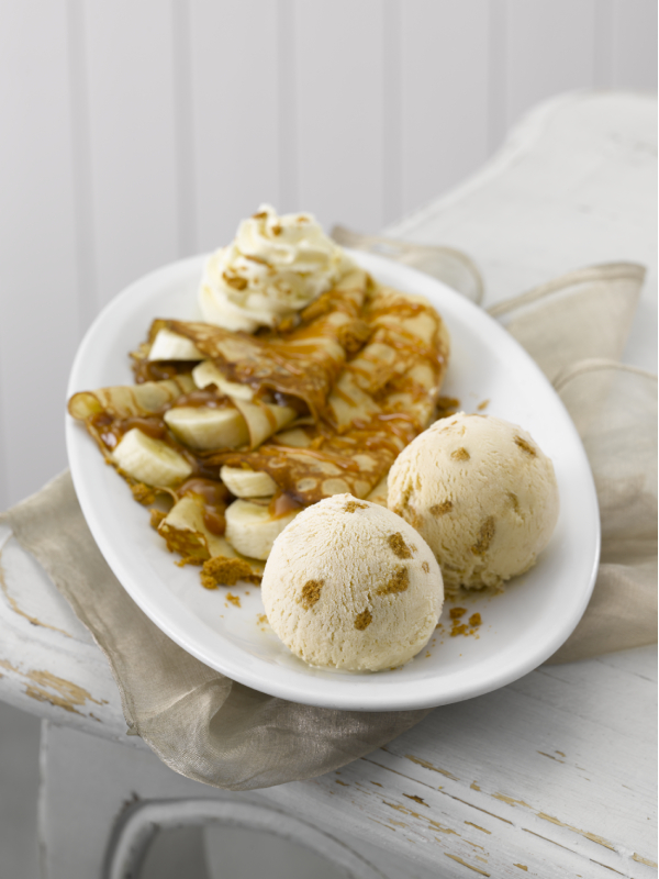 A plate containing two ice cream scoops and some banana slices with caramel.